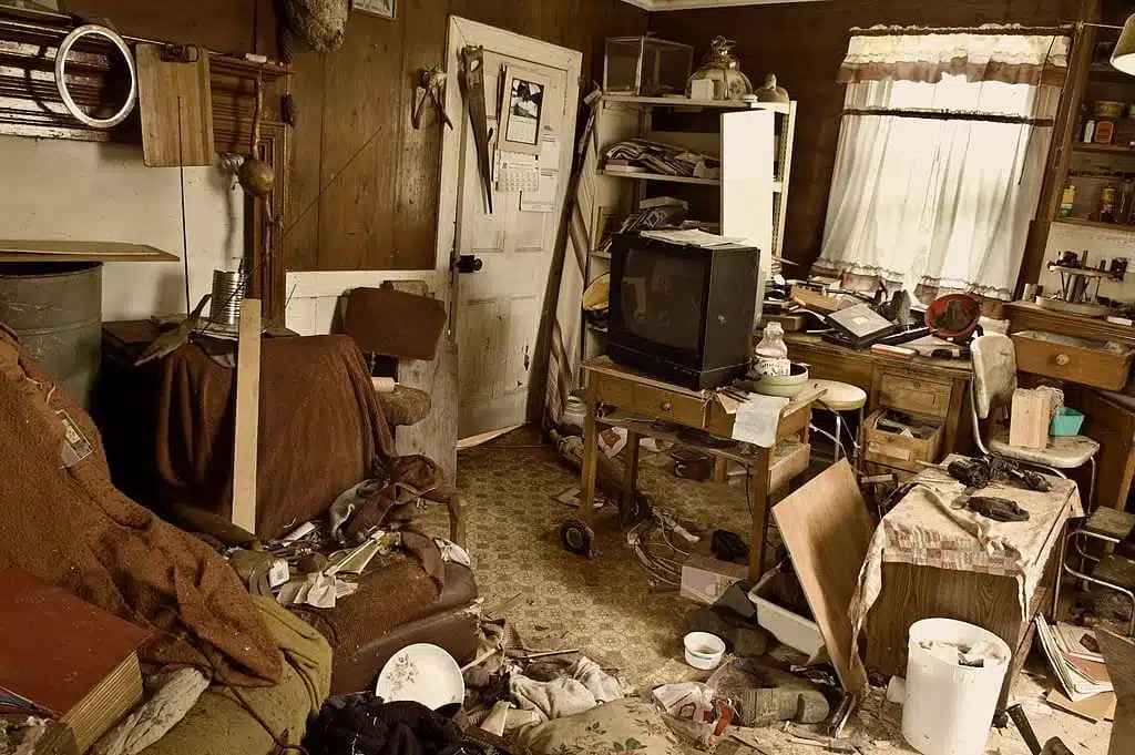 A room full of clutter with a TV in the middle surrounded by hoarder's items