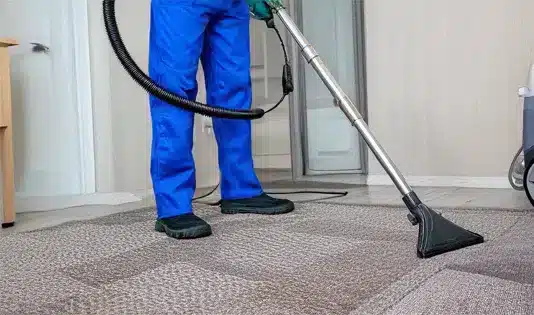 A cleaning technician's midsection while vacuuming residential upholstery