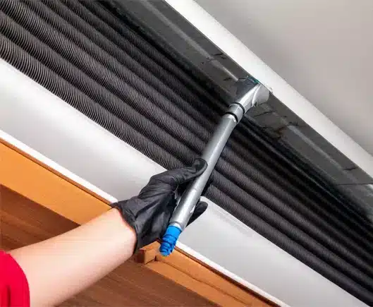 A cleaner's hand removing the cover of an air duct in a commercial space.