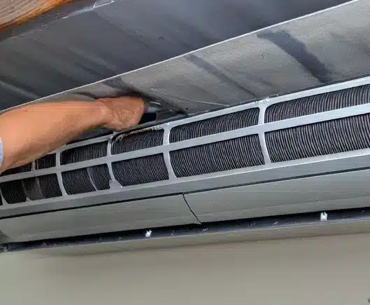 A cleaning technician's arm maintaining an air duct