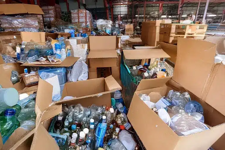 There is a large accumulation of boxes filled with bottles, plastics, and other items